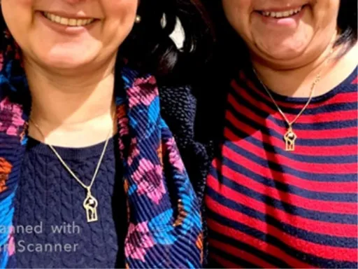 two women smiling with matching necklaces